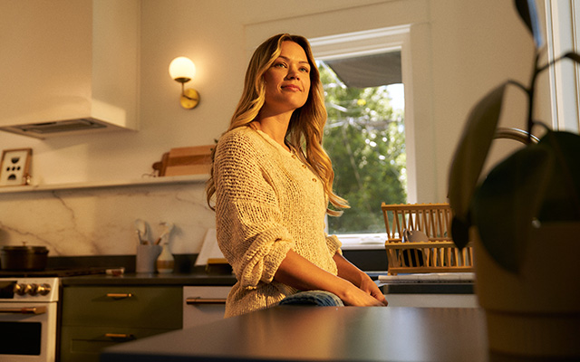 Young woman smiles while looking off into the distance while standing in kitchen